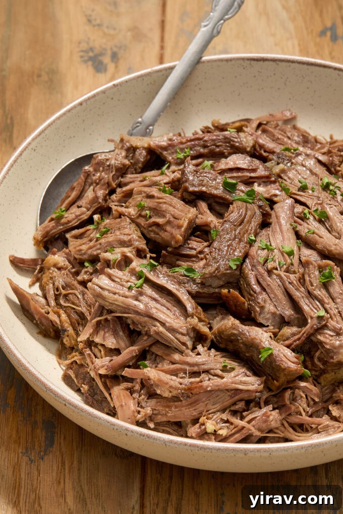 A bowl of slow cooker braised beef short ribs, garnished with fresh parsley, highlighting their tenderness.