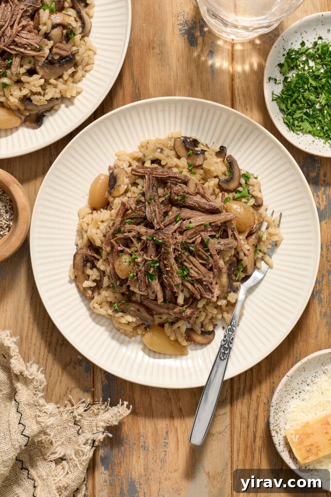 A serving of Beef Short Rib Risotto on a white plate, with a fork ready to enjoy.