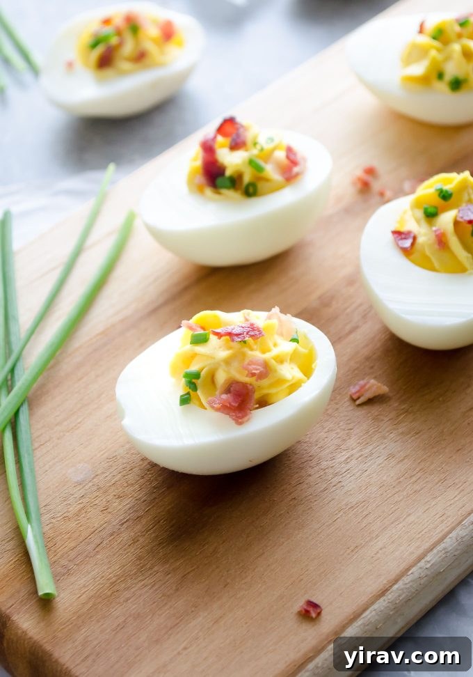 Deviled eggs with bacon on a cutting board with chives