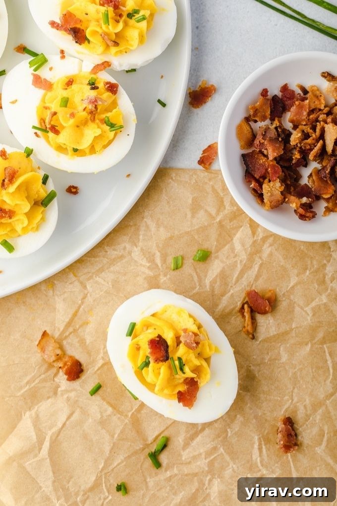 Bacon deviled eggs on a plate with bowl of bacon