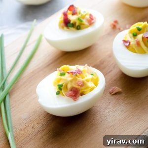 Deviled eggs with bacon on a cutting board with chives
