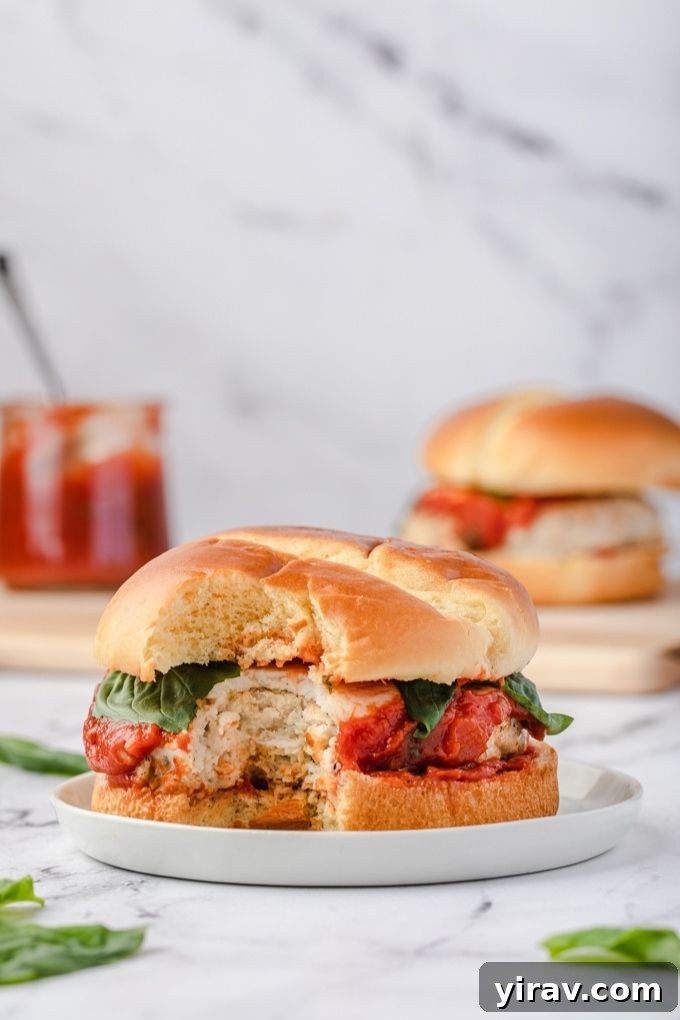 Ground chicken parmesan burger with a bite taken out, showing the juicy patty, melted cheese, and marinara