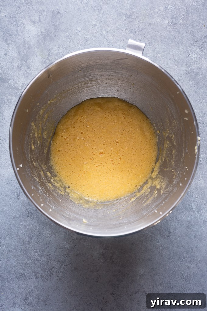 Eggs being added one at a time to the butter and sugar mixture, ensuring proper incorporation.