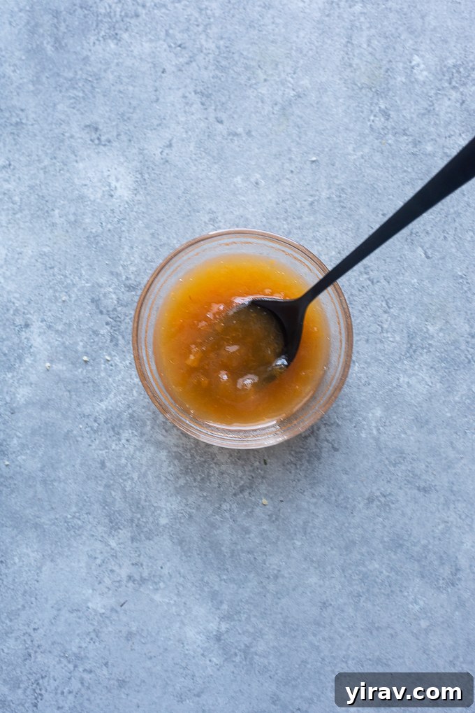Small bowl containing warm apricot jam mixed with water for a glossy fruit glaze.