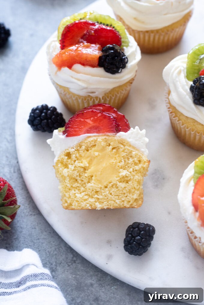 Fruit tart vanilla cupcake cut in half, revealing the creamy pastry cream filling and moist vanilla cake.