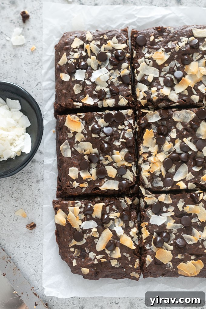Coconut brownies cut into squares on parchment paper