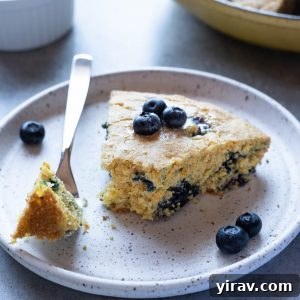 Slice of blueberry cornbread on plate with a fork