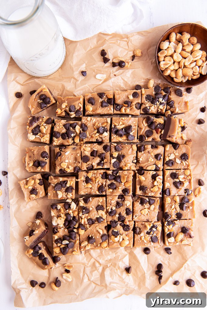 Squares of chocolate peanut butter fudge cooling on parchment paper, ready to be cut, highlighting their perfectly set layers and smooth texture.