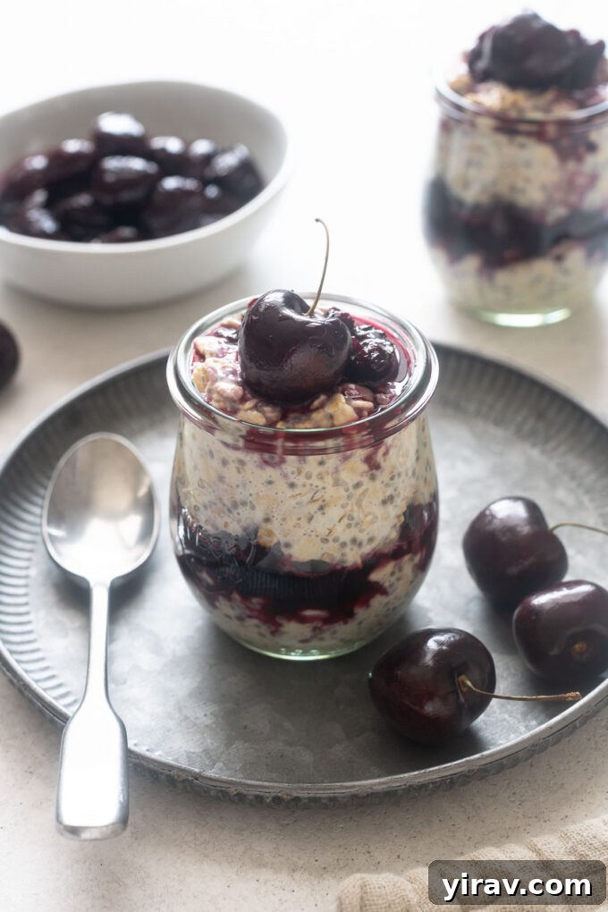 Beautifully presented Cherry Pie Overnight Oats in a jar, surrounded by fresh cherries.