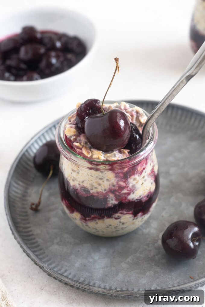 A close-up shot of creamy overnight oats with cherries in a glass jar, ready to be enjoyed.