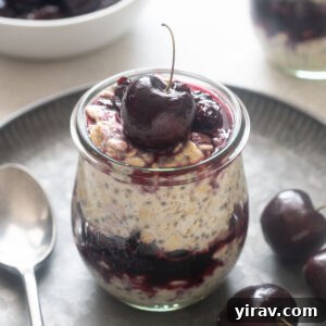Cherry pie overnight oats in a jar with a cherry on top.