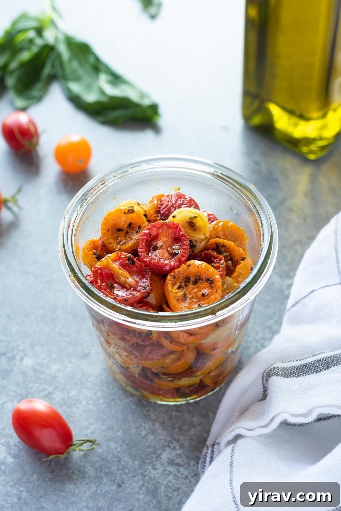 Oven roasted cherry tomatoes in a jar with basil and olive oil behind