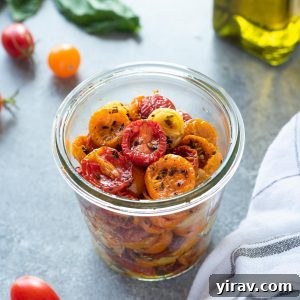Oven roasted cherry tomatoes in a jar with basil and olive oil behind