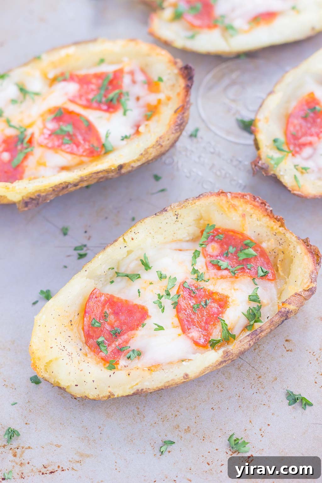 31 Tailgating Snacks That Steal the Show 11 Pizza potato skins generously topped with cheese and pepperoni, baked on a baking sheet.