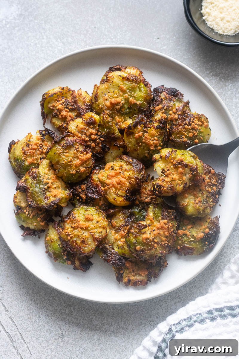 31 Tailgating Snacks That Steal the Show 15 A plate of perfectly smashed brussels sprouts, golden and crispy, with a serving spoon.