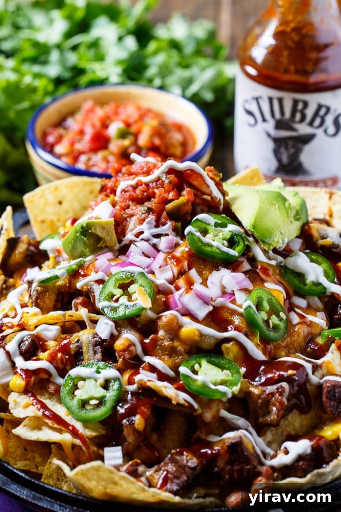 31 Tailgating Snacks That Steal the Show 21 A large plate overflowing with savory BBQ steak nachos, loaded with toppings.