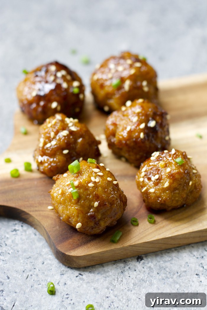 31 Tailgating Snacks That Steal the Show 23 Succulent Asian meatballs artfully arranged on a cutting board, garnished with fresh herbs.
