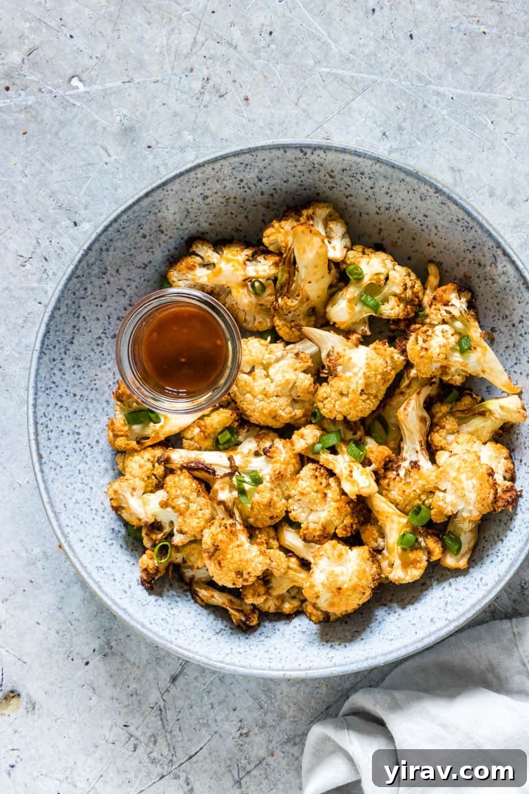 31 Tailgating Snacks That Steal the Show 29 A bowl overflowing with crispy air fryer buffalo cauliflower wings, drizzled with sauce.