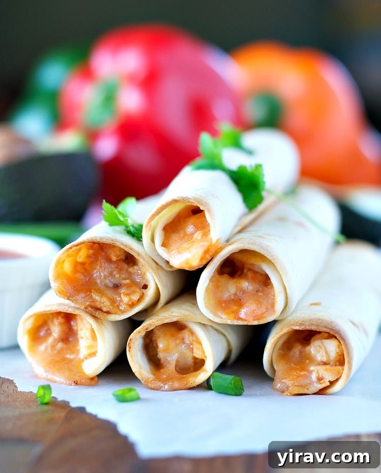 31 Tailgating Snacks That Steal the Show 9 A generous pile of crispy 4-Ingredient Chicken Taquitos on a white plate.