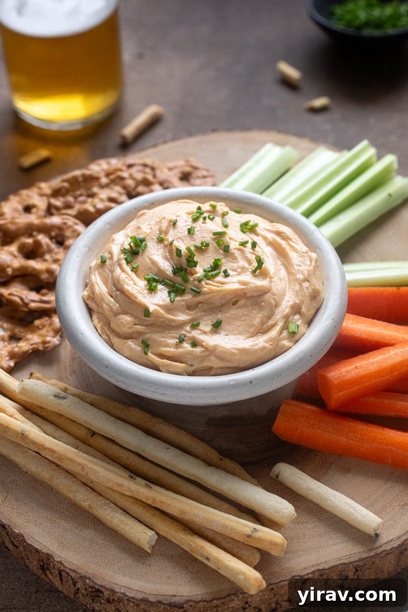 31 Tailgating Snacks That Steal the Show 10 Creamy homemade Cheddar Pub Cheese in a rustic bowl, garnished with fresh chives.