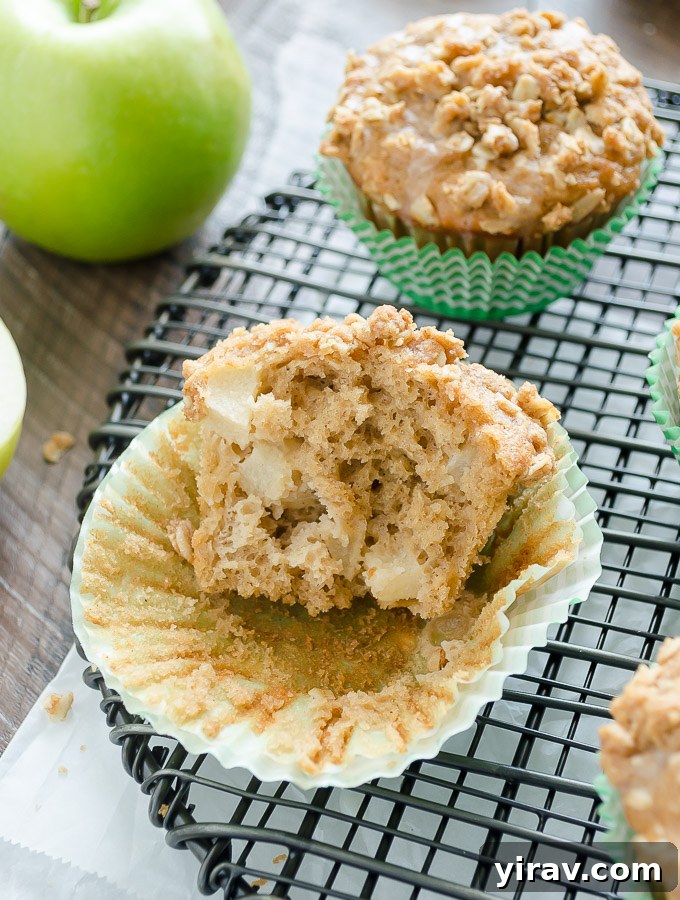 Two healthy apple muffins, one cut in half to show the tender apple chunks inside.