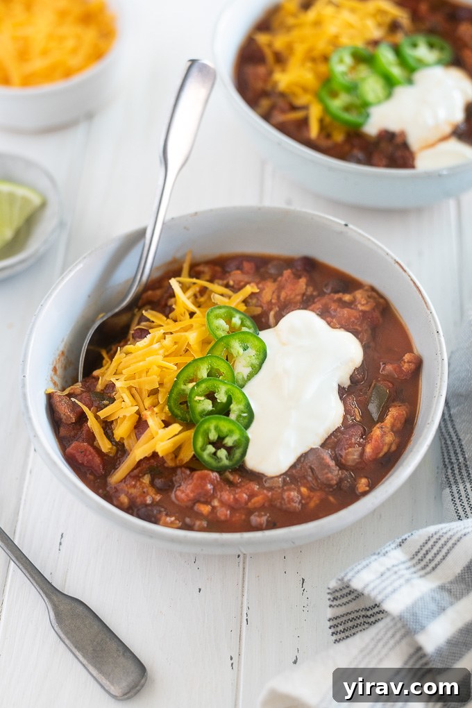 A vibrant bowl of Crock Pot Turkey Chili, generously topped with an assortment of fresh and colorful garnishes like avocado, cilantro, and red onions.