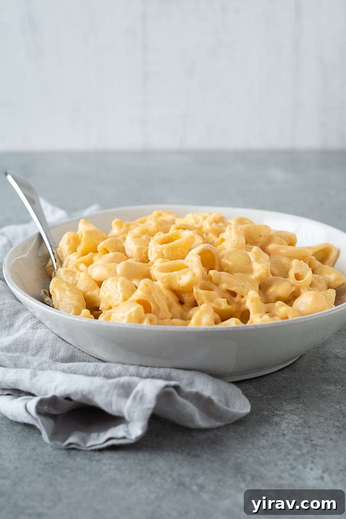 A pot of creamy one-pot mac and cheese in a white bowl, garnished with fresh parsley and a rustic linen.