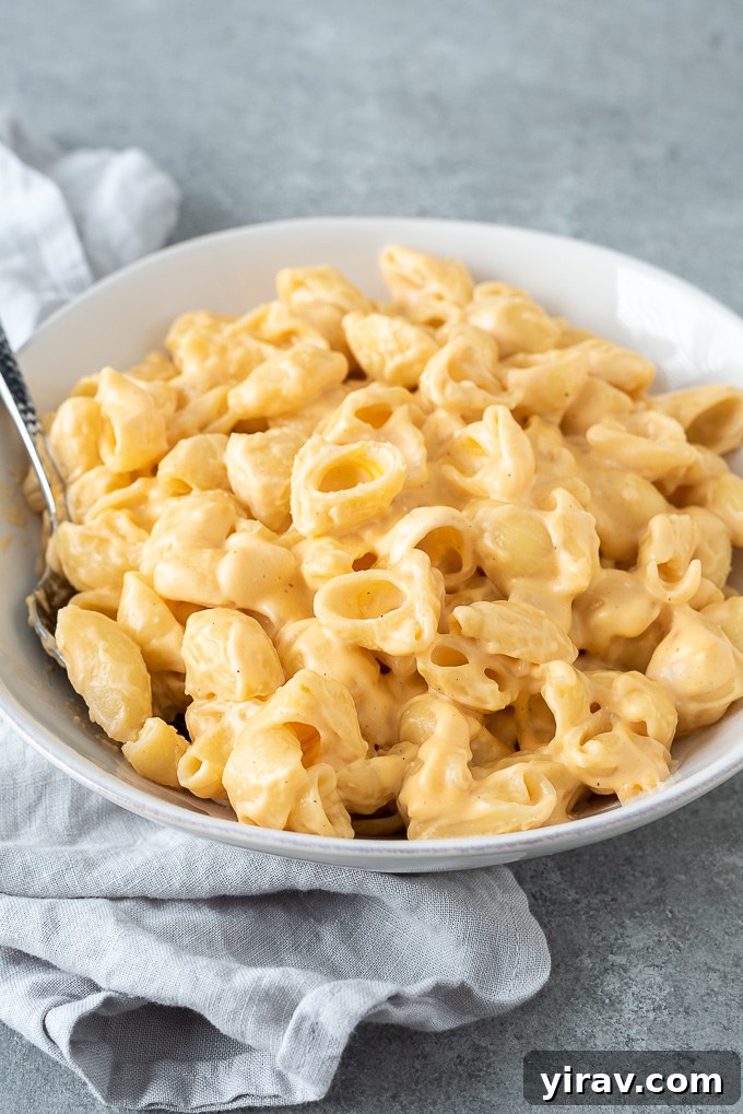 A large pot filled with creamy one-pot mac and cheese, with a serving spoon resting in it.