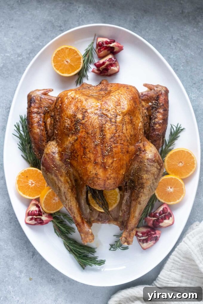 The Ultimate Dry Brined Roast Turkey 3 A whole roasted turkey, glistening with crispy, golden-brown skin, presented on a rustic wooden platter. The turkey is subtly garnished.