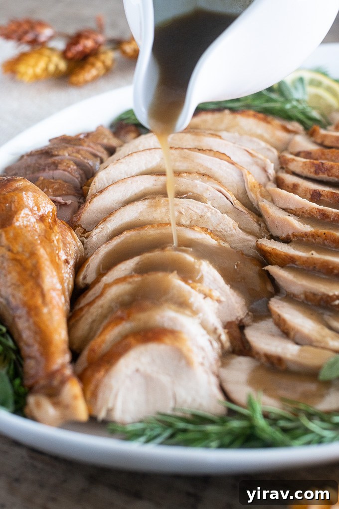 The Ultimate Dry Brined Roast Turkey 7 A close-up of carved roast turkey on a platter, with a gravy boat pouring rich gravy over the meat, highlighting its succulence.