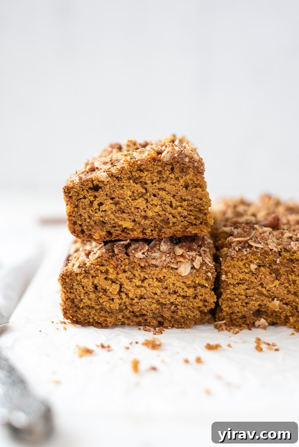 A stack of golden-brown pumpkin coffee cake slices gracefully arranged on a marble board, highlighting the rich texture and tempting streusel.