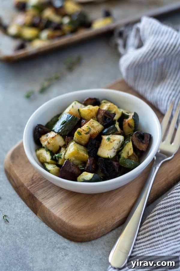 Roasted zucchini and mushrooms in a white bowl with a fork, ready to be served