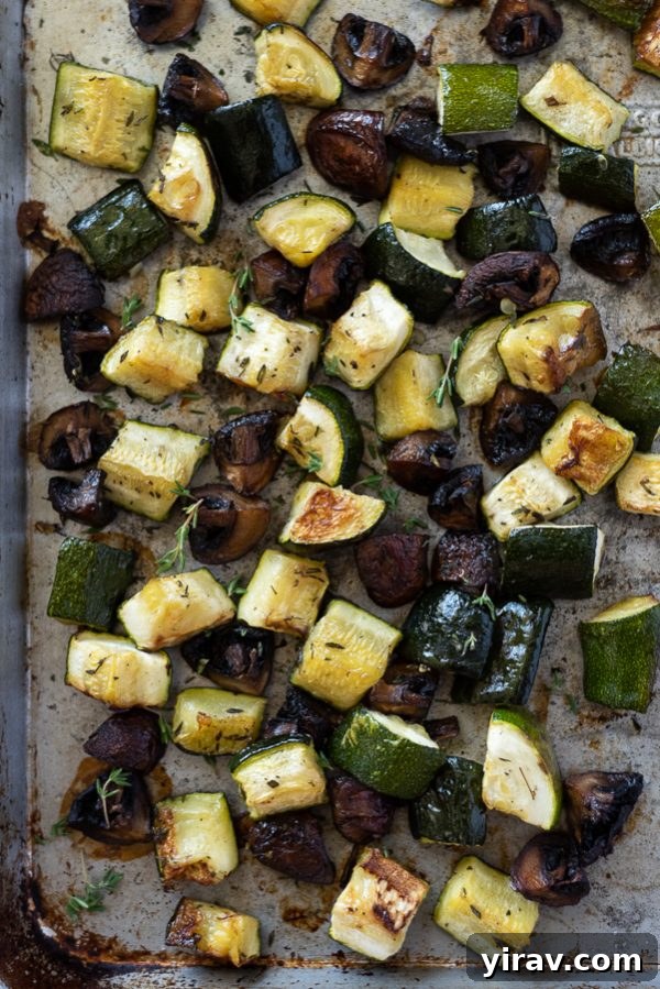 Sheet pan filled with caramelized roasted zucchini and mushrooms, fresh out of the oven