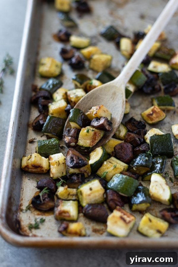Roasted zucchini and mushrooms on a sheet pan with a wooden spoon, ready to be served or stored