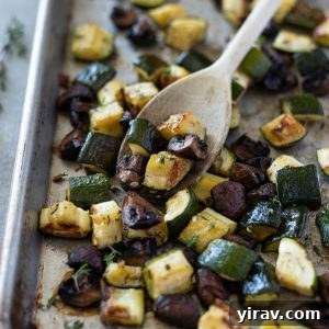 Roasted zucchini and mushrooms on a sheet pan with a wooden spoon