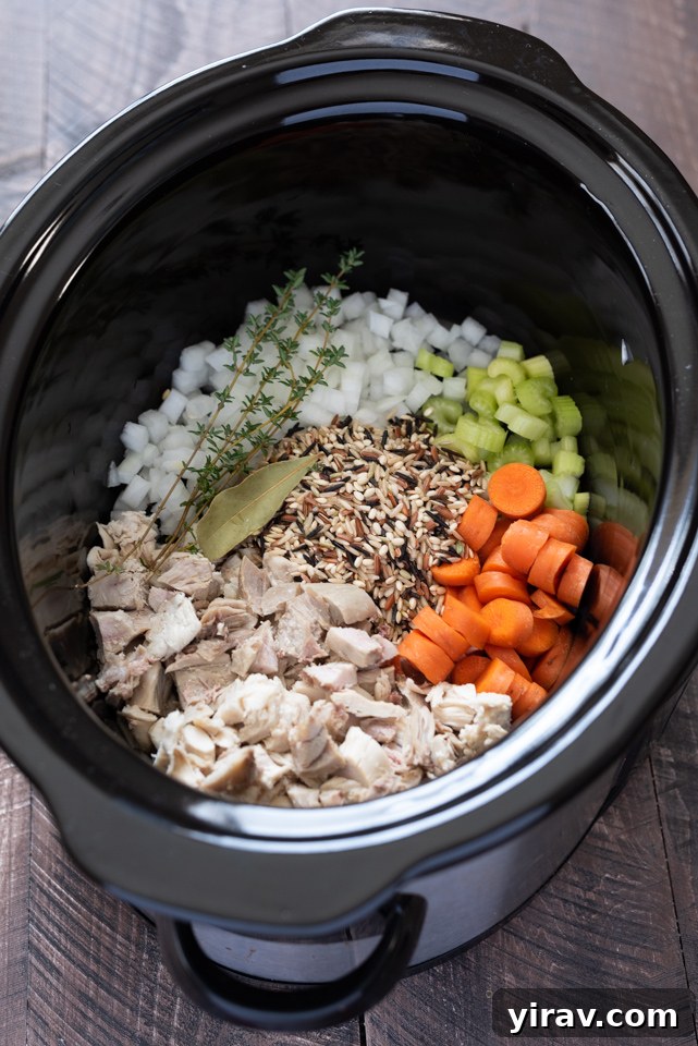 Ingredients for Slow Cooker Turkey Wild Rice Soup including cooked turkey, vegetables, wild rice, and fresh herbs.
