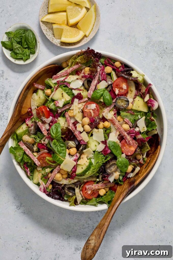 Italian chopped salad beautifully arranged in a bowl, ready to be served with elegant wooden salad servers.