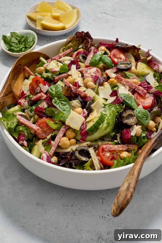 Close-up of chopped Italian salad in a white bowl, garnished with fresh basil leaves, highlighting the textures and colors.