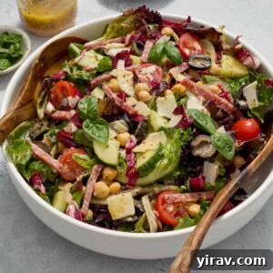 Italian chopped salad in a bowl with jar of dressing and basil.