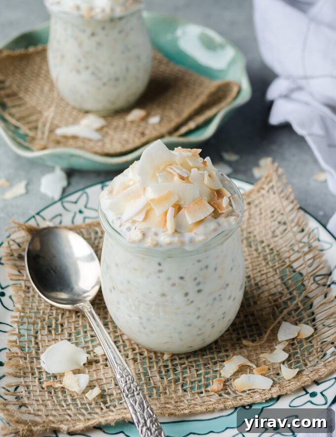 Overnight oats made with coconut, topped generously with fluffy coconut flakes in a glass jar.