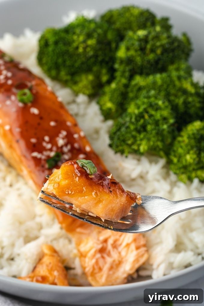 Glazed Teriyaki Salmon 7 A fork gently flaking into a perfectly cooked piece of baked teriyaki salmon on a plate, showcasing its tender texture.