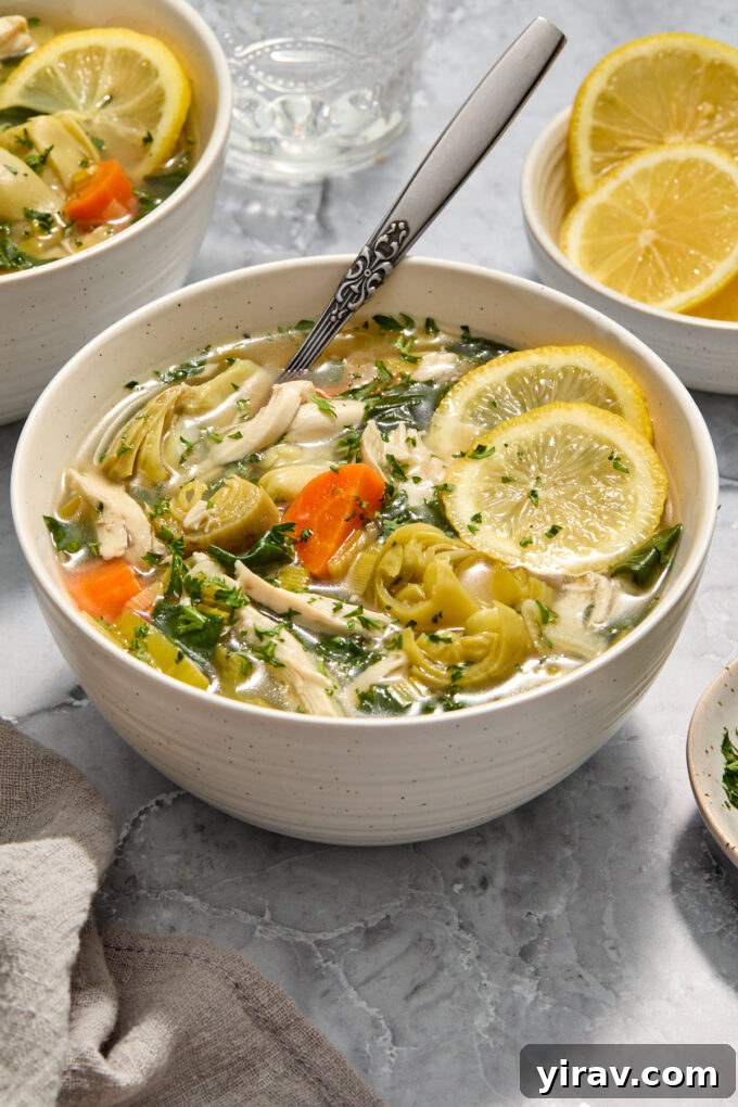 Lemon chicken soup with artichokes in a bowl.