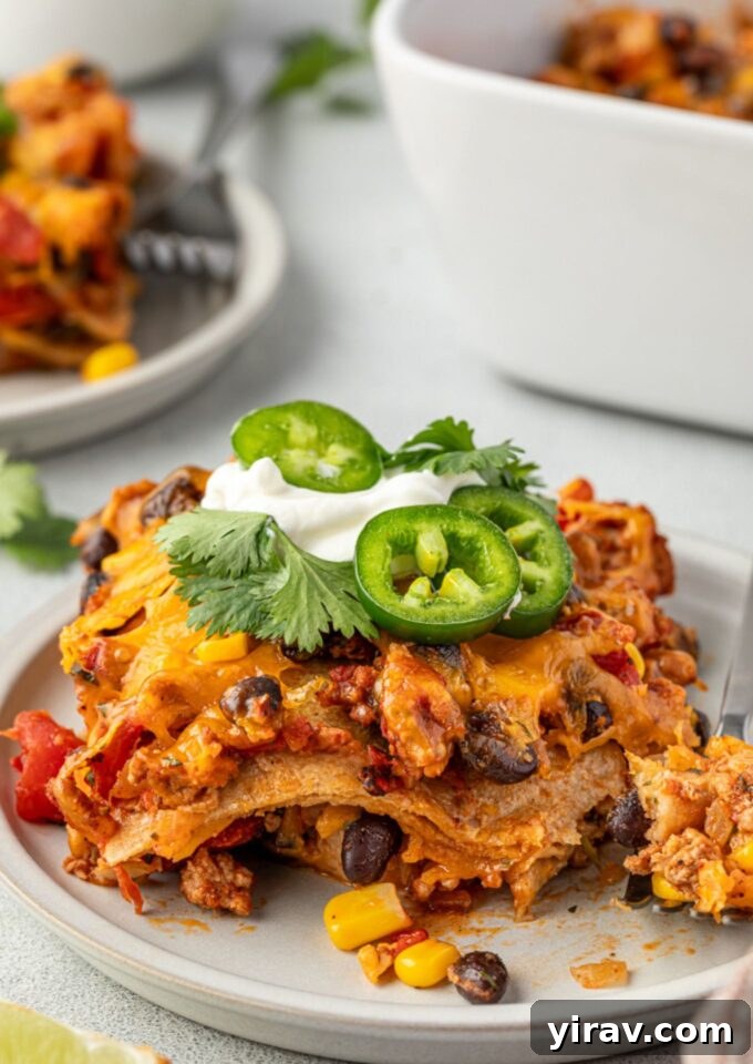 Serving of Mexican tortilla casserole topped with sour cream and jalapeno