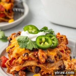 Serving of Mexican tortilla casserole topped with sour cream and jalapeno
