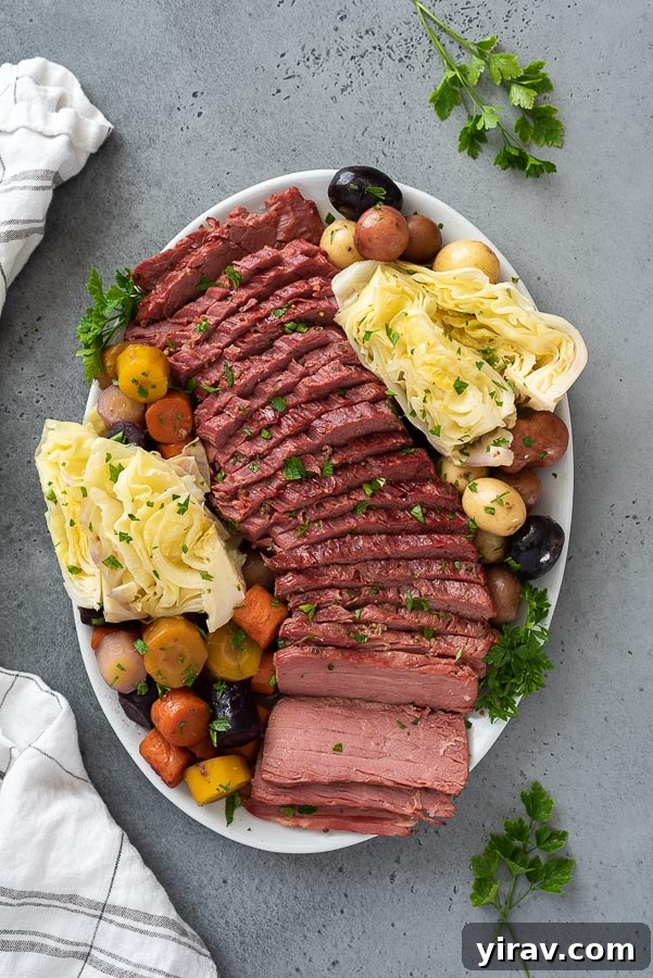Distant overhead shot of a large white platter showcasing a complete Corned Beef and Cabbage meal with beautifully sliced beef, neatly arranged cabbage wedges, potatoes, and carrots.