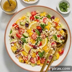 Greek orzo salad in a bowl with salad servers.