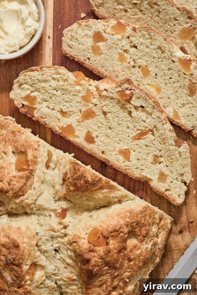 Sliced Irish soda bread with apricots and orange zest on a cutting board, ready to serve.