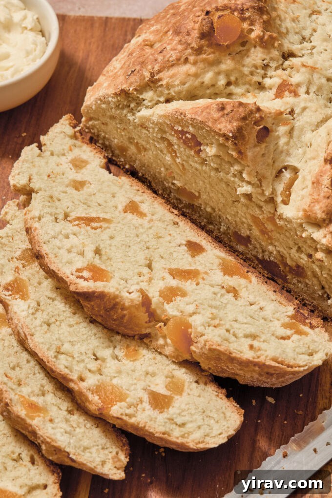 Sliced Irish soda bread with orange zest on a cutting board, ready to be spread with butter or jam.