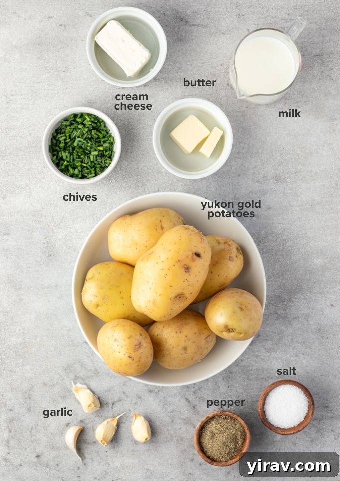 Sumptuous Yukon Gold Mashed Potatoes 4 A collection of fresh ingredients laid out, including Yukon Gold potatoes, garlic cloves, cream cheese, butter, and a glass of milk.