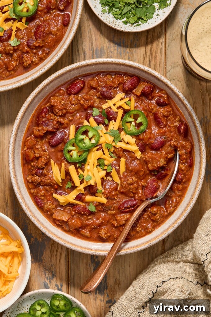 Rich Guinness Chili 2 Guinness chili with ground beef in a bowl, topped with shredded cheese and fresh jalapeno slices.